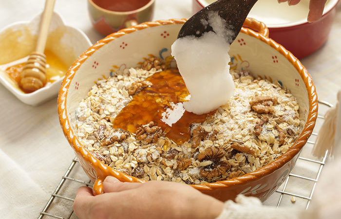 Adding coconut oil in a bowl to make granola