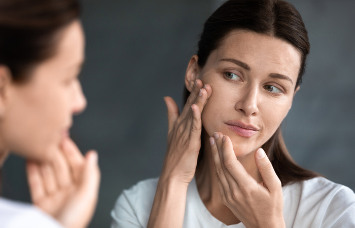 Woman checking her dry skin in the mirror