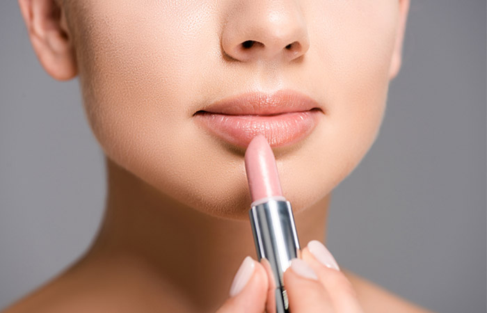 Woman applying nude lipstick to balance out the look