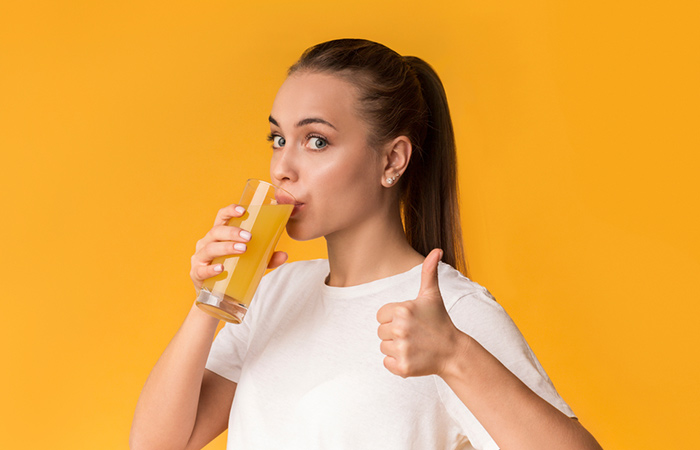 Woman relieving constipation by drinking orange juice