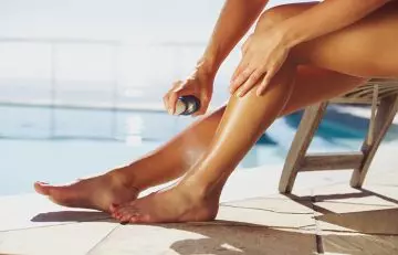 Close up of a woman using an aerosol spray on her legs