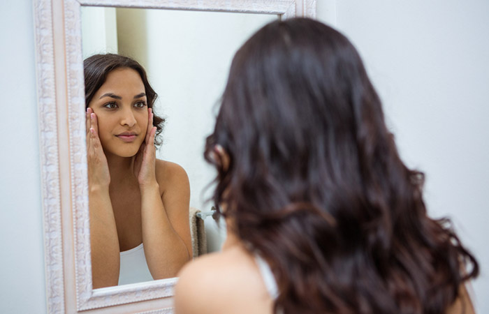 Woman checking her skin in a mirror