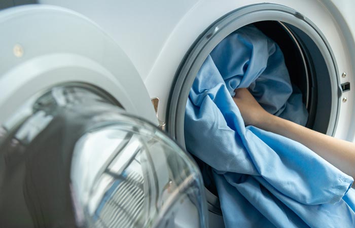 Person giving bedsheet for wash in the washing machine to prevent ringworm