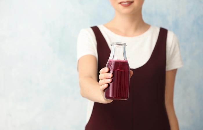 Woman holding a bottle of fresh and natural prune juice