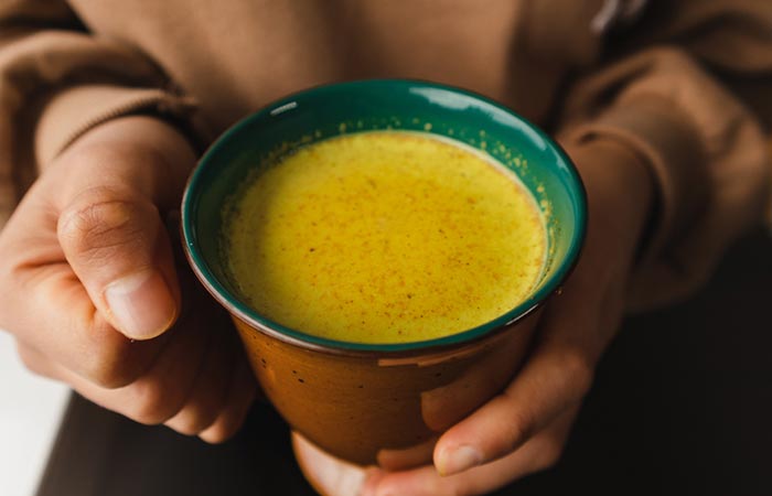 Close up of a woman's hands holding turmeric milk