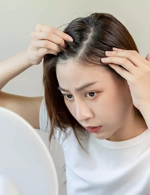 Woman with thin hair looking in the mirror