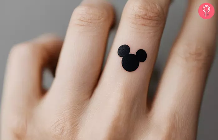 A minimalist Mickey Mouse head silhouette on the middle finger.