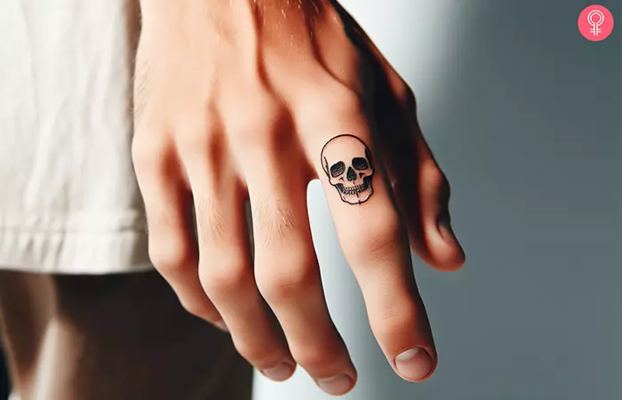 A minimalist skull outline tattoo on the index finger
