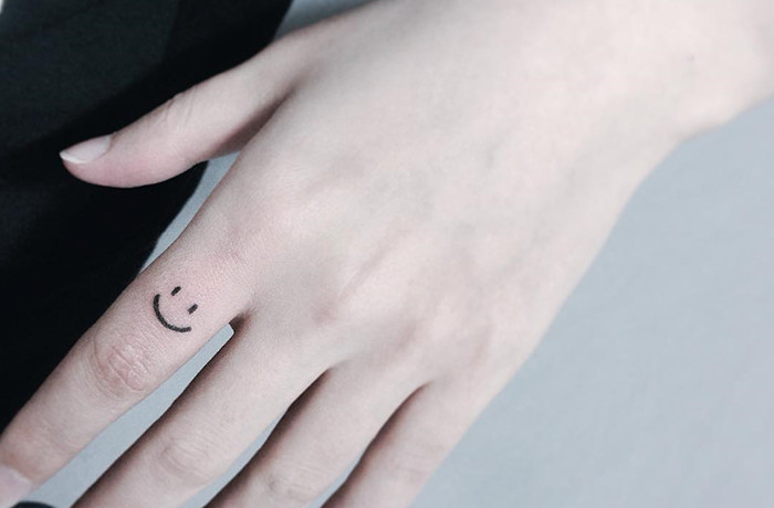 Smiley face tiny finger tattoo