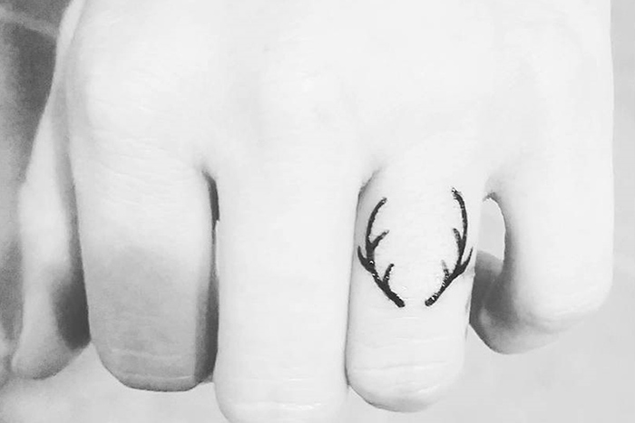 Tiny antler tattoo on finger