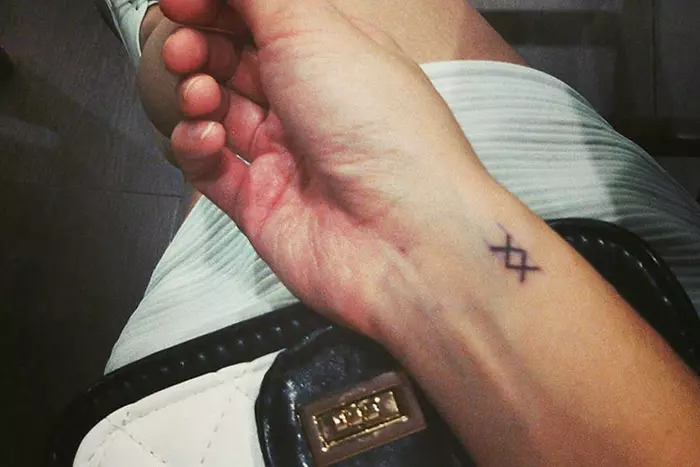 The double-cross tiny tattoo stands for Roman numerical 12