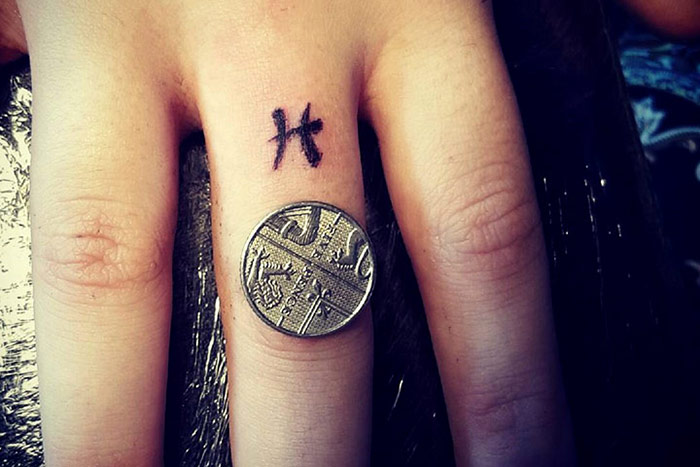 Tiny tattoo of the Pisces zodiac symbol