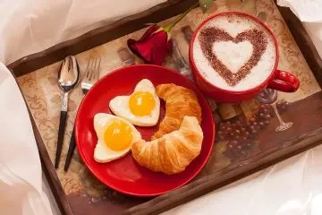 Breakfast in bed with heart shaped eggs and bread for Valentine's Day on a budget