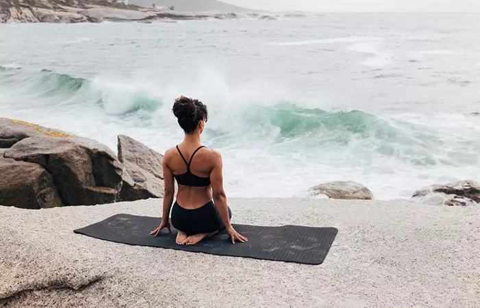 Woman doing vajrasana facing the ocean