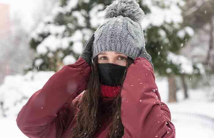 Woman covering her face to prevent redness due to cold weather.