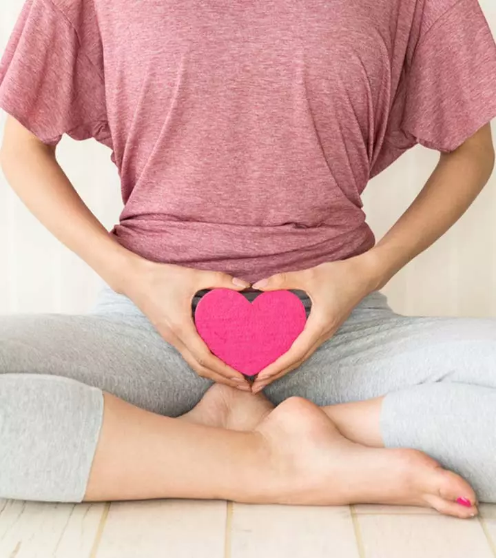 A woman holding up a heart in front of her lower tummy
