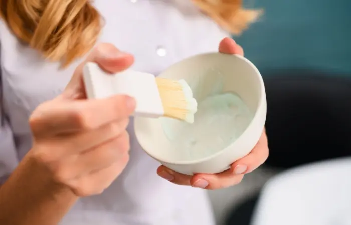 Woman mixing toothpaste with ground ginger and apple cider vinegar in a bowl