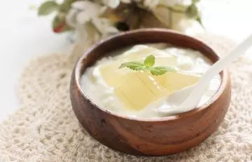 A bowl of yogurt and aloe vera mix with mint leaf on top