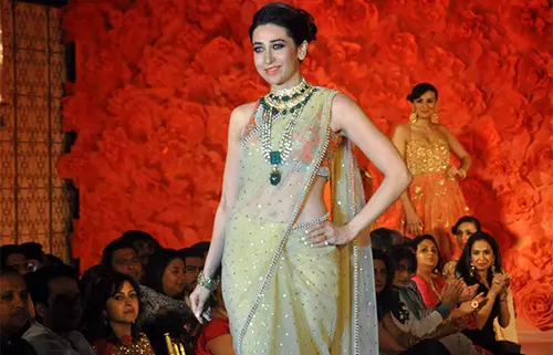 Karishma Kapoor in a nude sheer net saree with orange embellished blouse