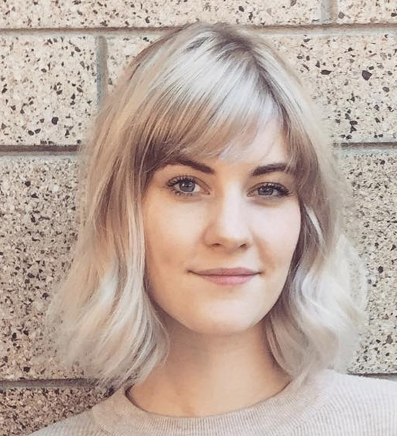 Short bob with side swept bangs colored all over in ash blonde hair color