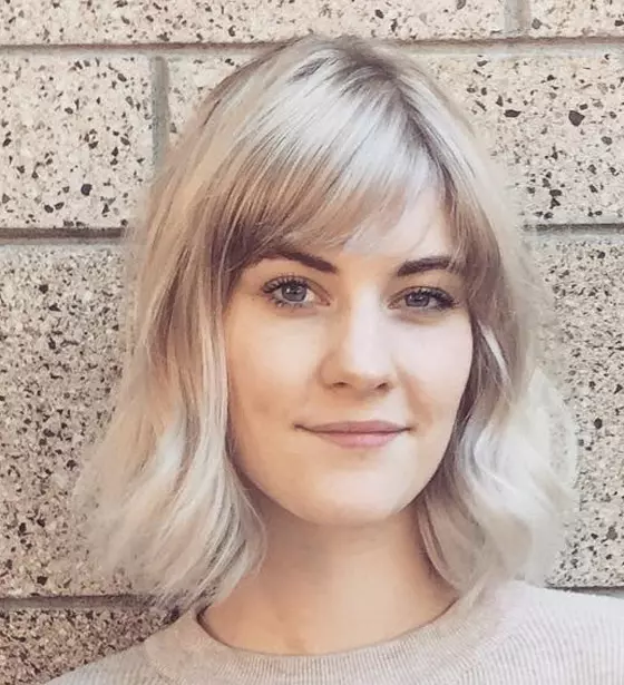 Short bob with side swept bangs colored all over in ash blonde hair color