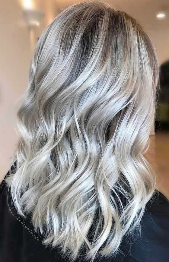 Medium length cut with some loose curls in icy white ash blonde hair color