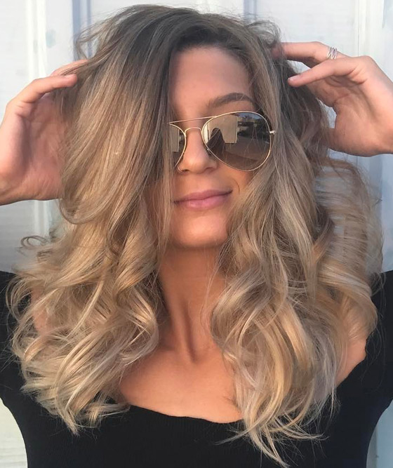 Warm roots and highlights run through cool toned ash blonde base hair color for a sunkissed effect