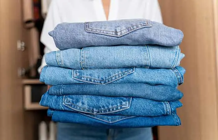 Woman holding a stack of jeans with different washes