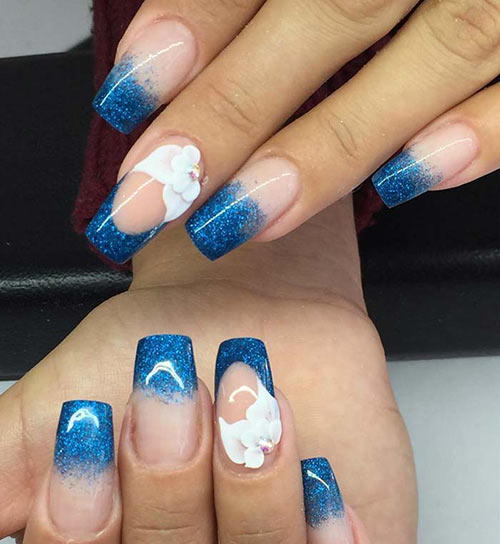 Blue glitter ombre acrylic nail design with flower accents