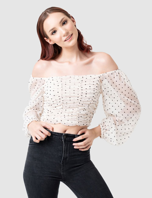 Woman wearing an off-shoulder crop top with black jeans.