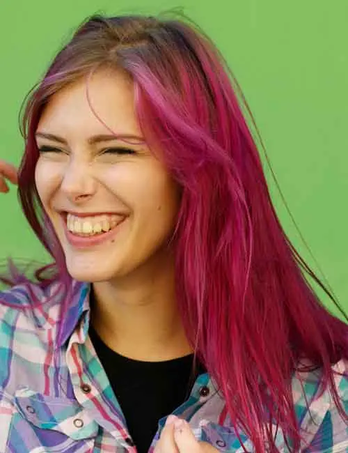 Portrait of a laughing woman with dark auburn hair and violet highlights