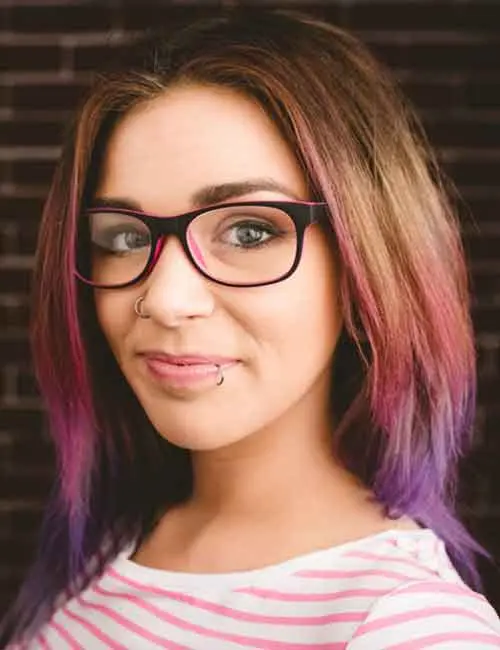 Portrait of a woman in eyeglasses with dark brown hair and purple highlights