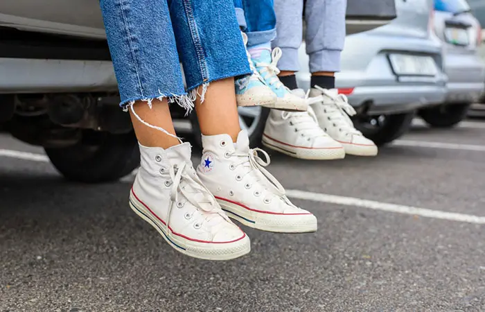 A woman wearing white Converse shoes