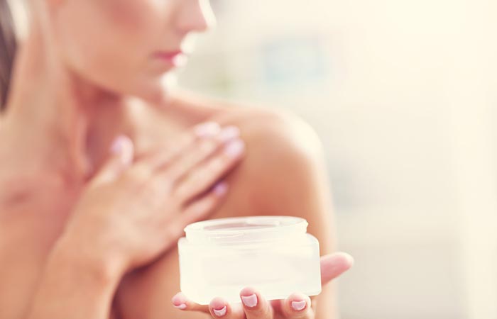Close up of a woman applying cream on her breasts.