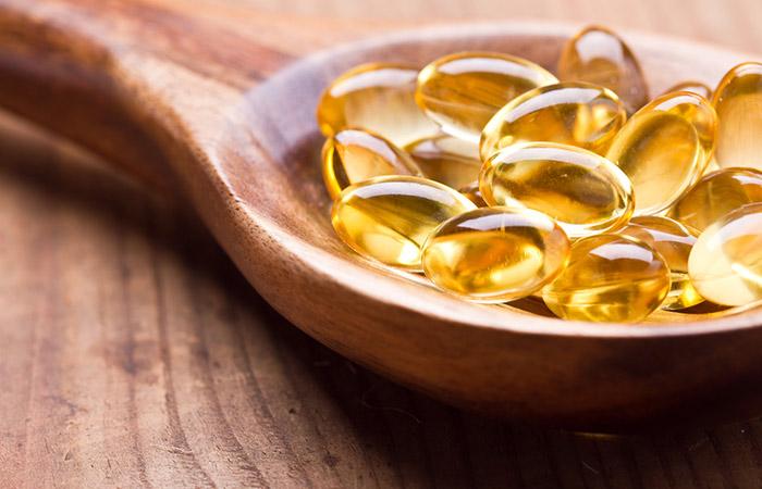 Close up of fish oil pills in a wooden spoon