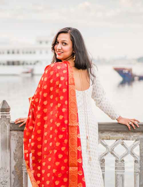 Woman wearing a red chanderi silk dupatta over a white Anarkali suit
