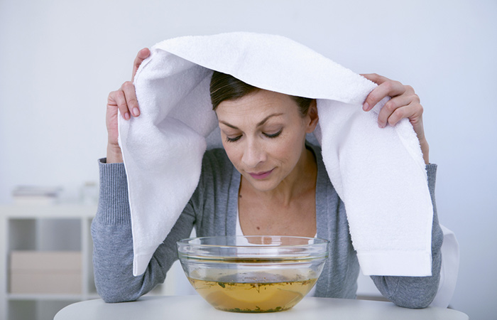 Woman with sinus infection inhaling steam from an essential oil