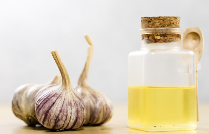 Garlic cloves with garlic juice in a bottle beside