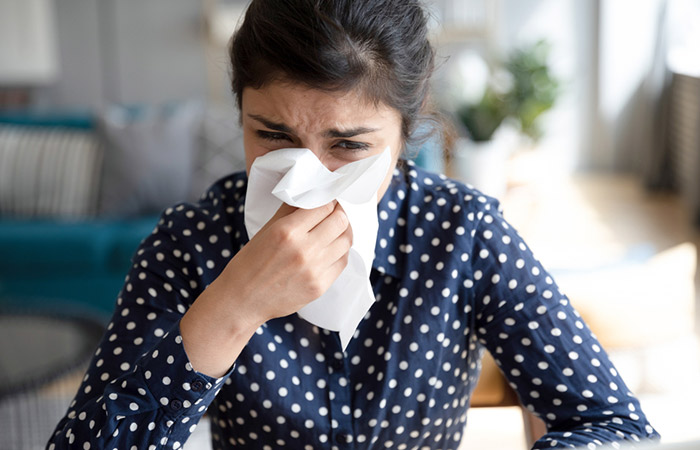 Woman using a tissue to sneeze