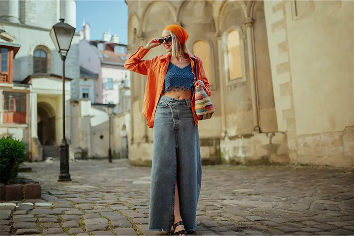 A woman wearing a long denim skirt with a crop top