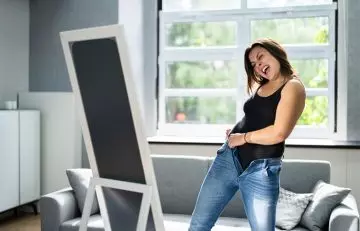 Woman stretching jeans in front of mirror