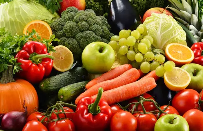 A happy woman enjoying a variety of fresh fruits and veggies.