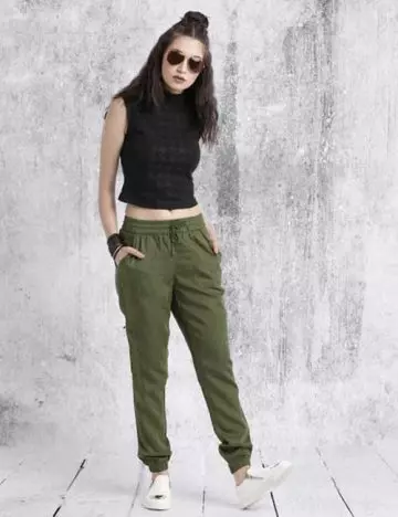 Olive green jogger pants with a crop top and big glasses