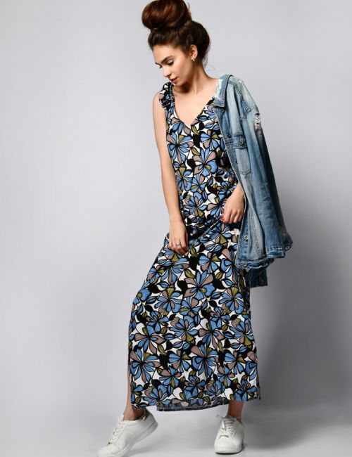 woman posing in a printed maxi dress and a denim jacket