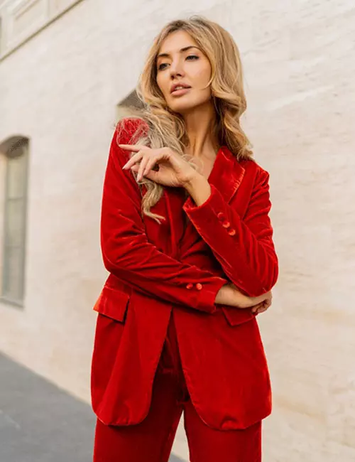 A woman wearing a vibrant red velvet suit for a formal wedding