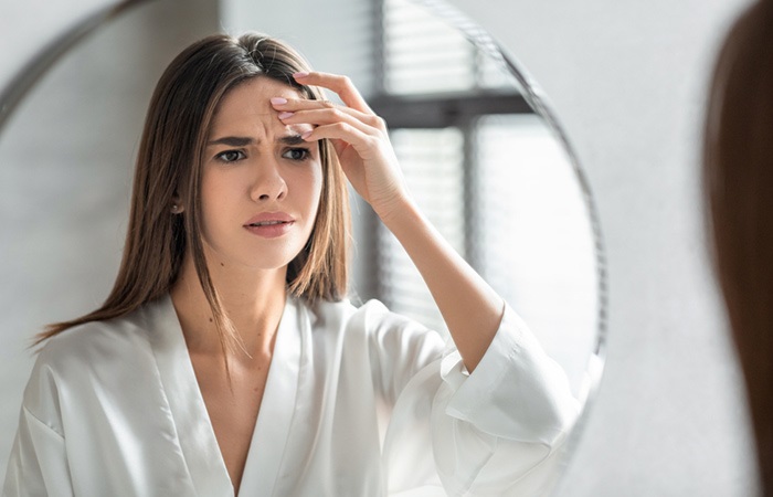 Woman checking her wrinkles in the mirror.