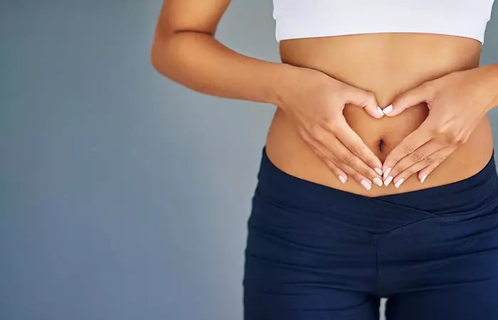 Woman making a heart sign over her stomach indicating gut health