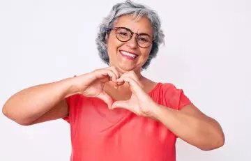 Woman makes a heart shape with hands to indicate a healthy heart