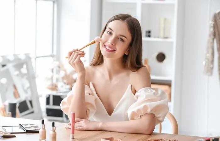 A smiling woman doing her makeup
