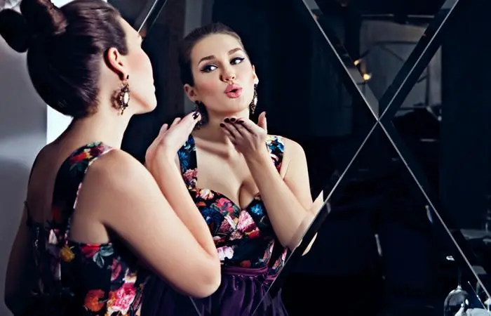 A woman blowing a kiss to her reflection on the mirror